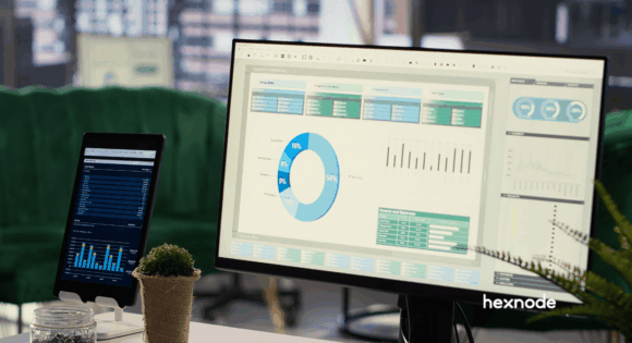 A desktop computer and tablet in an office, each displaying comprehensive data monitoring dashboards with colorful charts and graphs, showcasing the Hexnode interface. This photo visualizes a unified approach to endpoint management when evaluating a Datto RMM alternative for diverse device fleets.