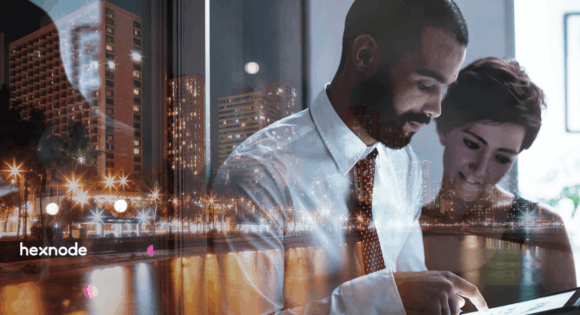 Double exposure of business professionals analyzing data on a tablet overlaid with a modern nighttime cityscape, representing secure IT compliance in the DACH region. Features the Hexnode logo.