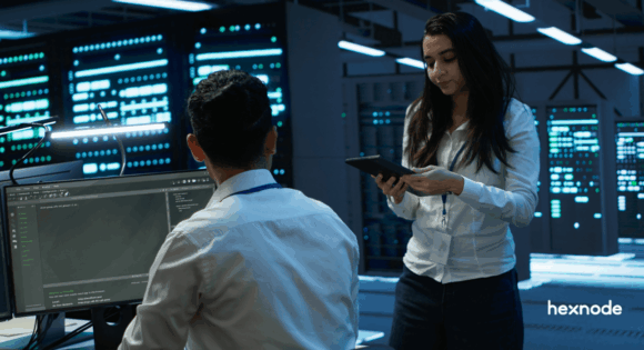 Colleagues in a modern data center analyzing network topology and data structures using a node tree software program.