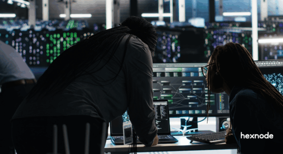 IT and SecOps professionals in a high-tech data center monitoring cyber security threats on large digital dashboard displays.