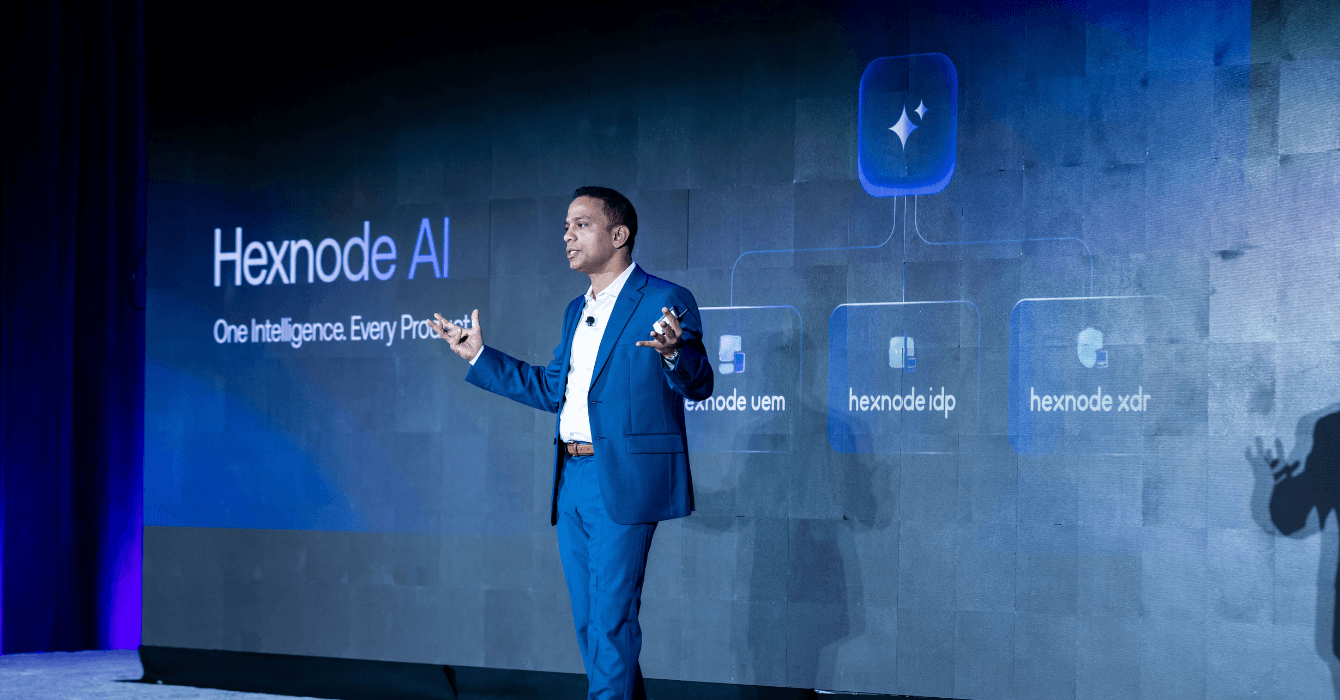 Apu Pavithran presenting Hexnode AI at HexCon26, with a diagram connecting it to Hexnode UEM, IdP, and XDR